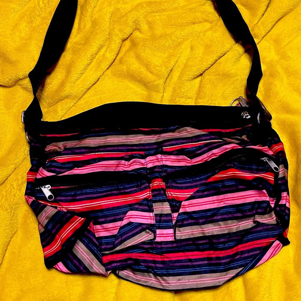 Crossbody nylon, multicolored striped purse with red purse keychain.